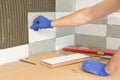 Closeup of tiler hand laying ceramic tile on wall in kitchen, renovation, repair, construction