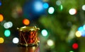 Closeup of a tiny drum Christmas ornament with a bright glowing tree in the blurry background Royalty Free Stock Photo