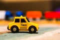 Closeup of a tiny taxi car toy on a wooden table on a blurry background