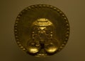 Closeup to an ancient indigenous rounded golden pectoral with a face