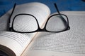 Closeup to a black glasses over a spanish book and blue background.