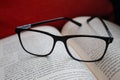 Closeup to a black glasses over a spanish book and orange background.