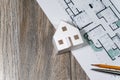 Closeup to floor plans, white paper house on wooden background. Architect drawings, expensive renovation, building construction