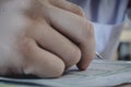 Closeup to hand of student holding pen and taking exam in classroom with stress for education test. Royalty Free Stock Photo