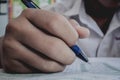 Closeup to hand of student holding pen and taking exam in classroom with stress for education test. Royalty Free Stock Photo