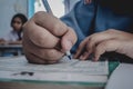 Closeup to hand of student holding pen and taking exam in classroom with stress for education test. Royalty Free Stock Photo