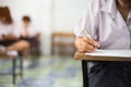 Closeup to hand of student  holding pen and taking exam in classroom with stress for education test Royalty Free Stock Photo