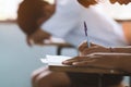 Closeup to hand of student  holding pen and taking exam in classroom with stress for education test Royalty Free Stock Photo