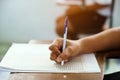 Closeup to hand of student  holding pen and taking exam in classroom with stress for education test Royalty Free Stock Photo