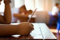 Closeup to hand of student  holding pencil and taking exam in classroom with stress for education test Royalty Free Stock Photo