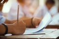 Closeup to hand of student  holding pencil and taking exam in classroom with stress for education test Royalty Free Stock Photo
