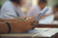 Closeup to hand of student  holding pencil and taking exam in classroom with stress for education test Royalty Free Stock Photo