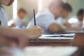 Closeup to hand of student  holding pencil and taking exam in classroom with stress for education test Royalty Free Stock Photo