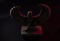 Closeup to a Isis. female old winged egyptian god mini figurine into darkness iluminated with white and red lights Royalty Free Stock Photo