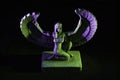 Closeup to a Isis. female old winged egyptian god mini figurine iluminated with green and violet lights