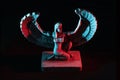 Closeup to a Isis. female old winged egyptian god mini figurine iluminated with red and blue lights Royalty Free Stock Photo