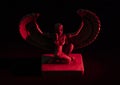 Closeup to a Isis. female old winged egyptian god mini figurine iluminated with red lights Royalty Free Stock Photo