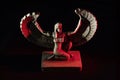 Closeup to a Isis. female old winged egyptian god mini figurine iluminated with white and red lights Royalty Free Stock Photo