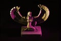 Closeup to a Isis. female old winged egyptian god mini figurine iluminated with yellow and pink lights Royalty Free Stock Photo