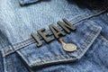 Closeup to a JEAN lettering black word over a gradient Blue jean jacket.