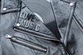 Closeup to a love music lettering art over a black leather biker jacket with LP vinyl disc