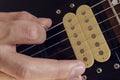 Closeup to a male hand holding a pguitar pick playing a black and yellow electric guitar Royalty Free Stock Photo