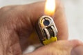 Closeup to a male hand holding a yellow lighter with flame on Royalty Free Stock Photo