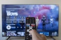 Closeup to a male right hand holding a black remote smart tv control with Amazon Prime streaming interface