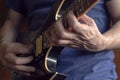 Closeup to a man wearing a blue navy t-shirt playing a black and yellow electric guitar with wooden background Royalty Free Stock Photo