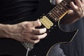 Closeup to a man wearing a leather jacket playing a black and yellow electric guitar with black background Royalty Free Stock Photo