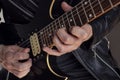Closeup to a man wearing a leather jacket playing a black and yellow electric guitar with black background Royalty Free Stock Photo