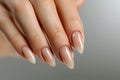 Closeup to woman hands with elegant neutral colors manicure. Beautiful nude manicure on long almond shaped nails. Nude