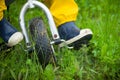 Closeup of toddler child feet in rubber boots and pants riding a bicycle on green grass. Boy walking outdoors Royalty Free Stock Photo