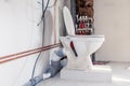 Close-up toilet on the block of aerated concrete on floor against background construction in bathroom, water copper and sewer