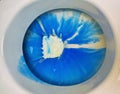 Closeup of toilet bowl seat with blue white environmantal harmful chemical chlorine aggressive cleaning detergent product