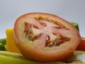 Closeup tomato cut in half placed among bell peppers and sweet peppers