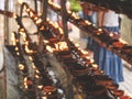 Closeup toned image of long rows of burning oil lanterns and lamps in the buddhist or hindu temple