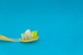 Closeup of toothpaste squeezed on a yellow toothbrush isolated on the blue background Royalty Free Stock Photo