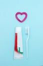 Closeup of a toothpaste, toothbrush and toothpaste heart on blurred blue background. Means to care for the oral cavity Royalty Free Stock Photo