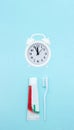 Closeup of a toothpaste, toothbrush and white alarmclock on blurred blue background. Dental Hygiene and Health conceptual image