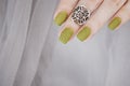 Closeup top view of beautiful painted in green nails isolated on grey lace background. Winter autumn nail style