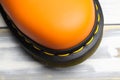 Closeup top view on bright orange color tip of one single leather boot, black sole, yellow stitching on white wood background