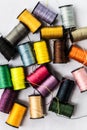 Closeup top view of colorful bobbins with sewing threads on white background