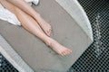 Closeup top view cropped shot of lower legs of unrecognizable young woman relaxing lying on deck chair by poolside after Royalty Free Stock Photo