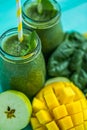 Closeup top view of green smoothie with mango, apple, spinach in glass jars. Turquoise blue table Royalty Free Stock Photo