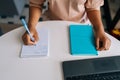 Closeup top view of unrecognizable African female student sitting at desk looking at computer screen making notes Royalty Free Stock Photo