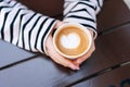 Closeup top view of unrecognizable young woman holding hot cup of coffee with heart shape. Close up cropped shot of Royalty Free Stock Photo