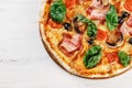 CLOSEUP Top view VERY HOT Italian Pizza on white wooden table with mushrooms, basil, tomato, olives and cheese. Look as Prosciutto Royalty Free Stock Photo