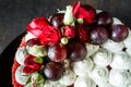 closeup topping of cake decorated with bizet, grapes and roses