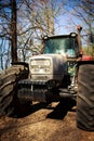 Closeup tractor bonnet big wheels on soil road in spring forest